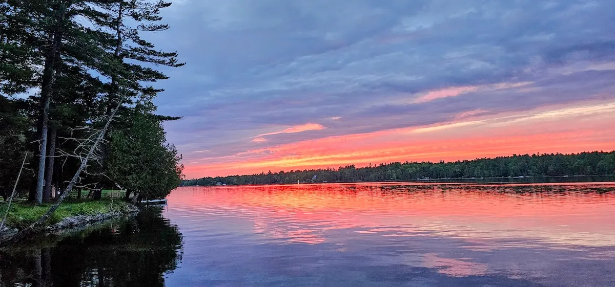 Sunset over White Lake, the water mirror-flat and the sky pink and violet